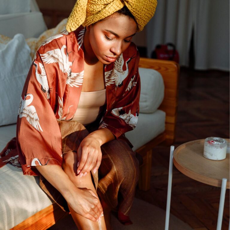 woman rubbing cream on legs